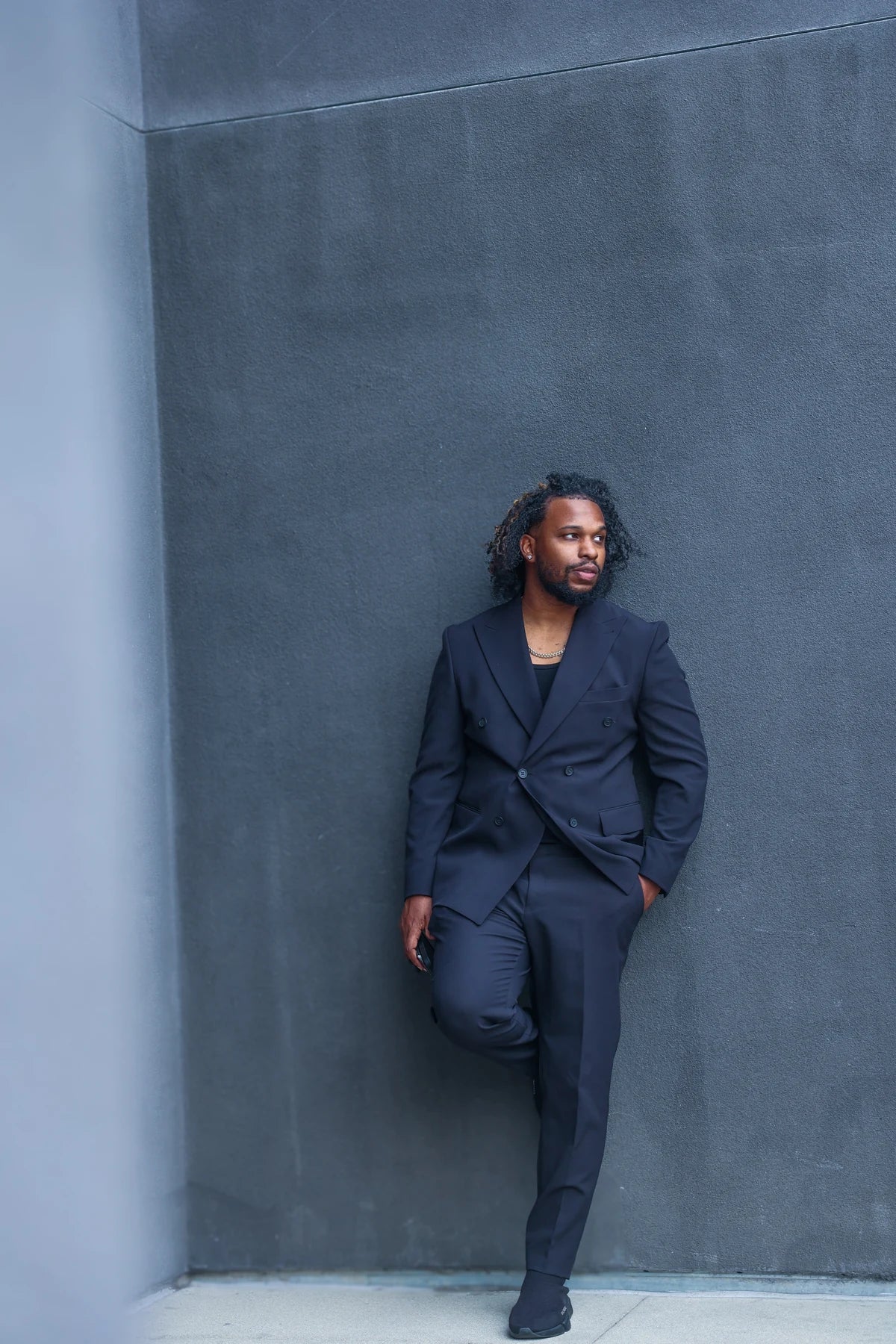 Hashim Lafond in a suit against an architectural wall